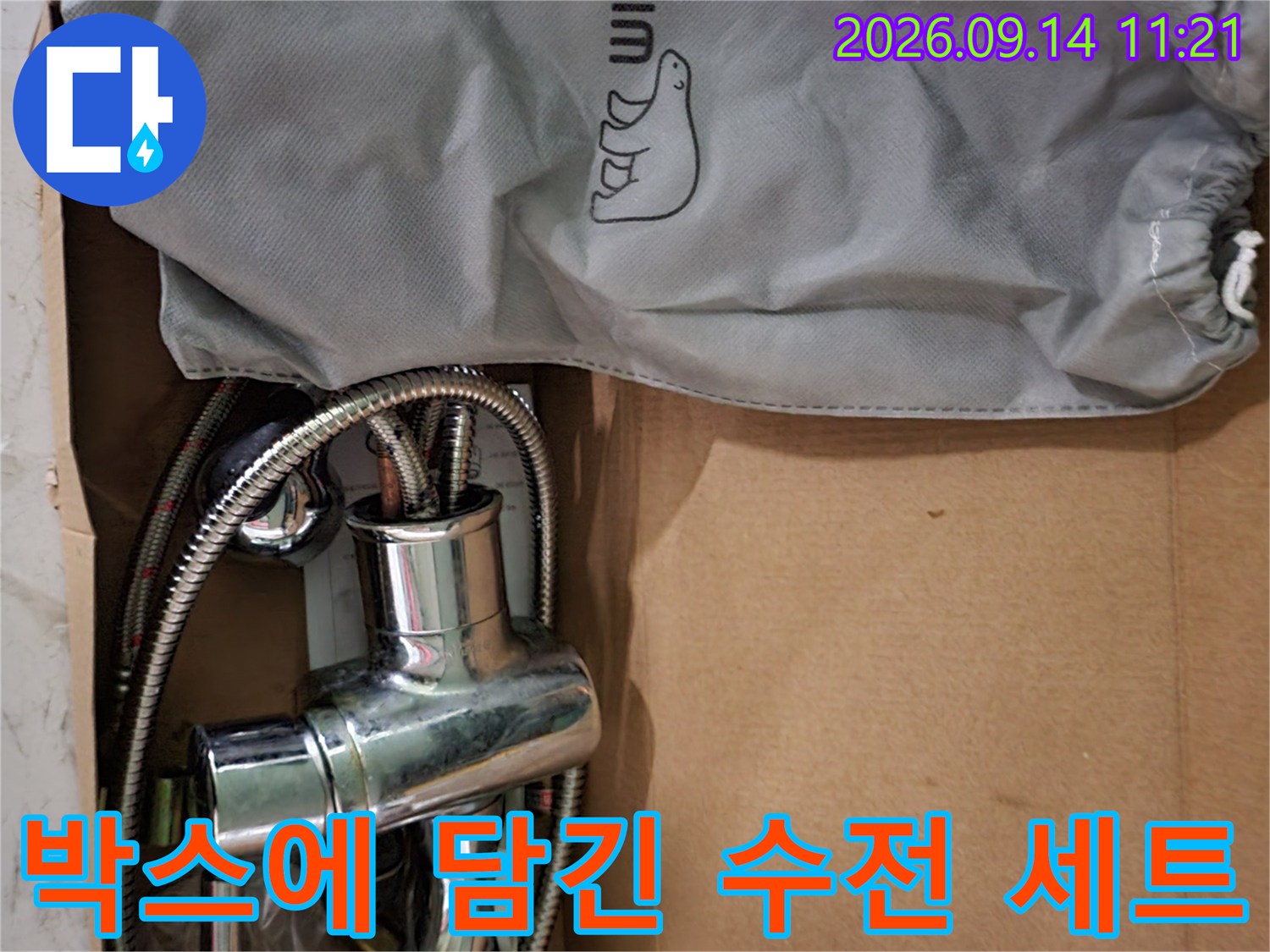 회색 파우치와 샤워기 수전이 들어있는 종이 상자