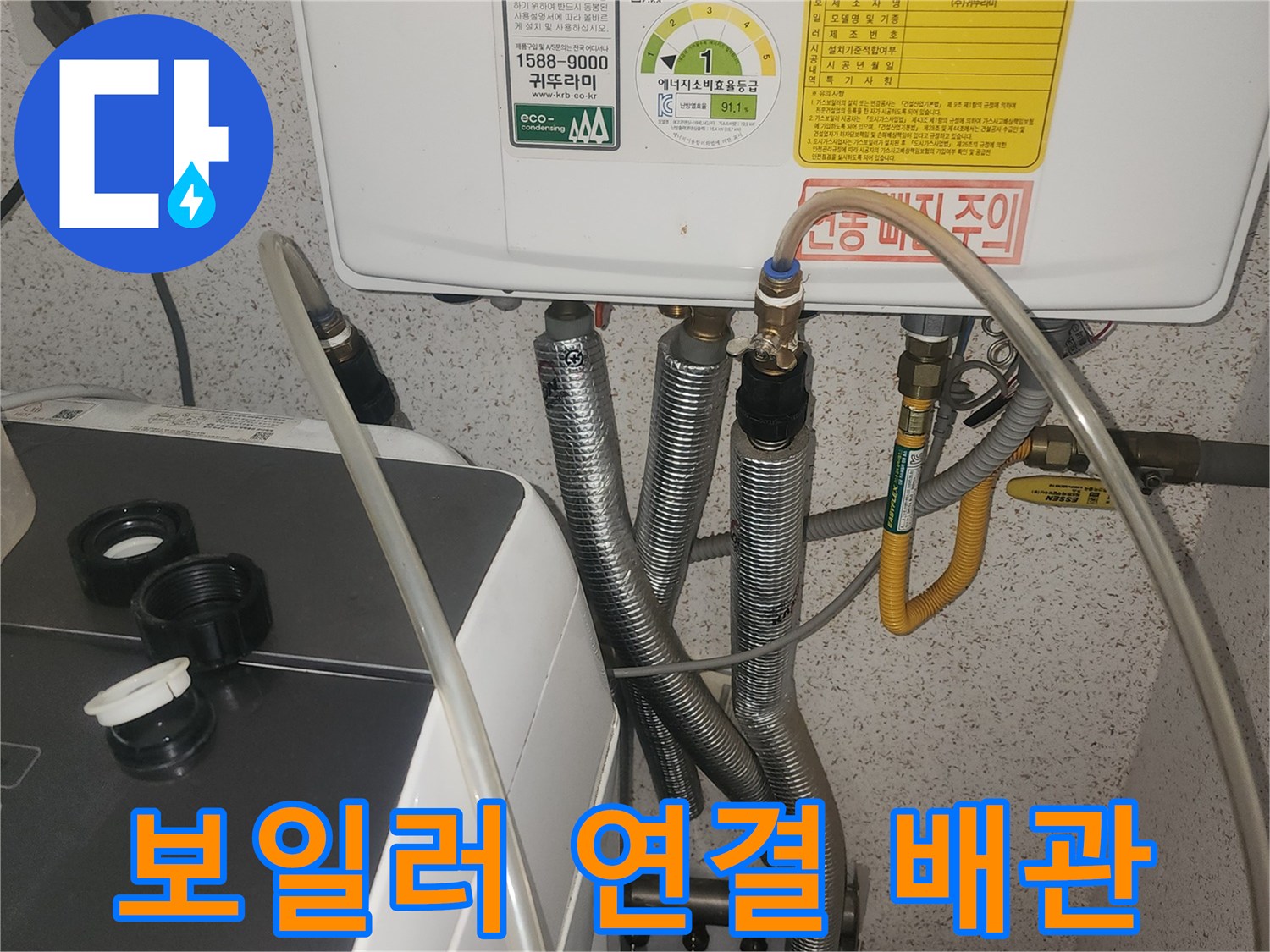 보일러 하단에 연결된 은색 주름관과 노란색 온수 배관 모습