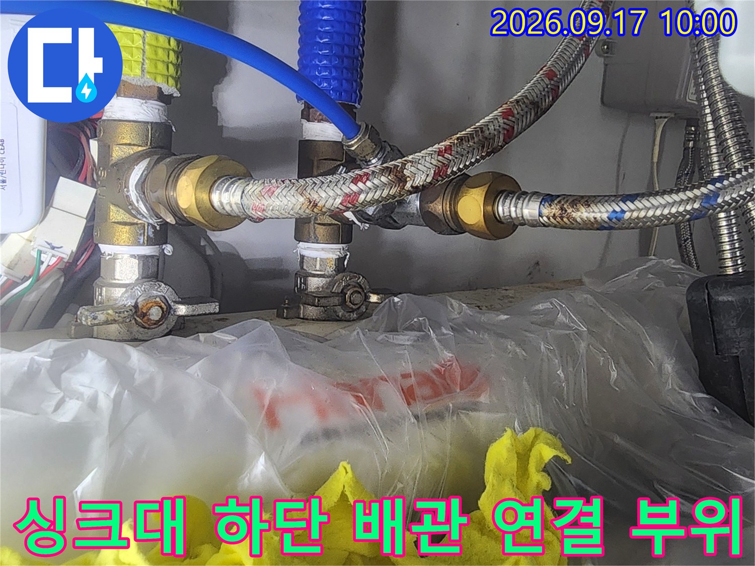 싱크대 아래쪽 수도 밸브와 금속 호스 연결 상태를 보여주는 사진