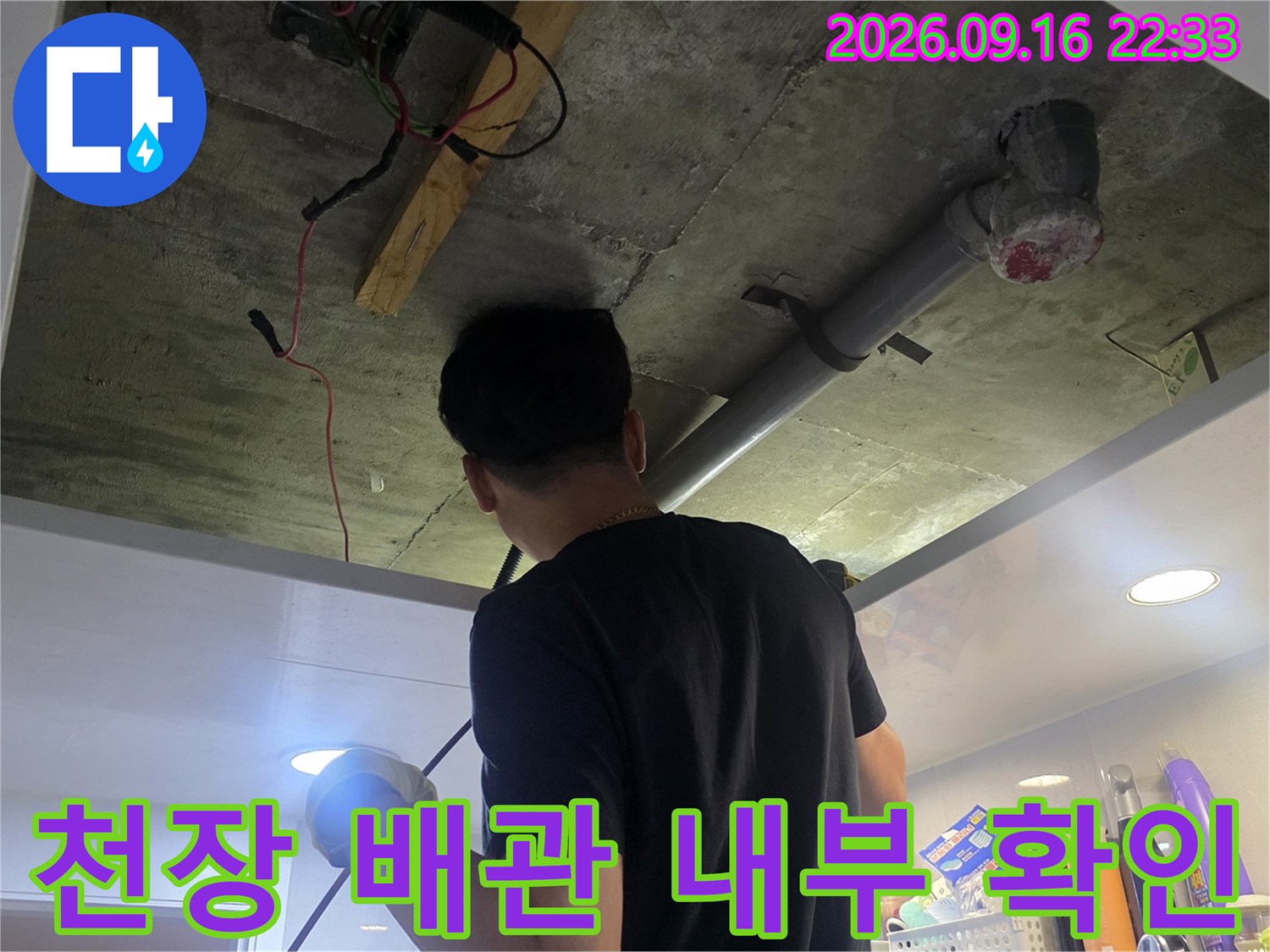 천장 점검구 안쪽의 배관 연결 부위와 주변 마감 상태를 점검하는 장면입니다.