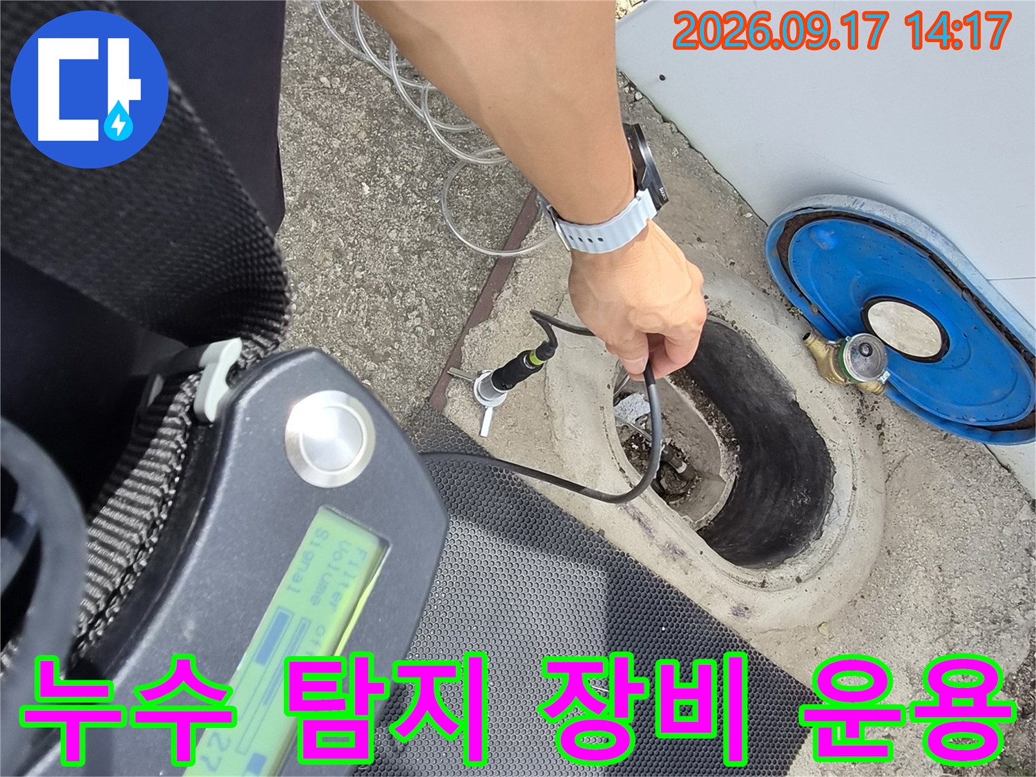 수도 계량기 주변의-배관 누수 지점을 찾기 위해 장비를 사용하는 모습
